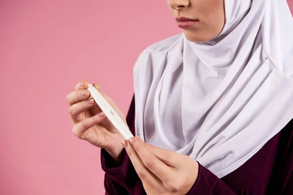 Arab worried woman in hijab holds pregnancy test