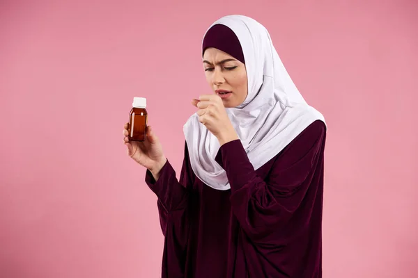 Arab woman in hijab with cough syrup