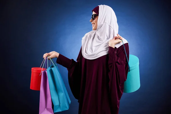 Arab woman in sunglasses holds paper colored bags