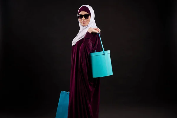Arab woman in hijab and sunglasses holds paper