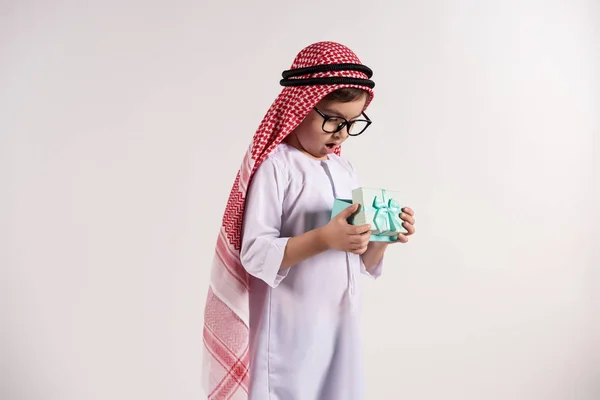 Arabian boy in keffiyeh opens present. — Stock Photo, Image