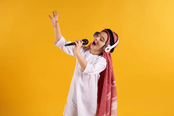 Arabian pojke i huvudbonaden med mikrofon sjunger karaoke. — Stockfoto