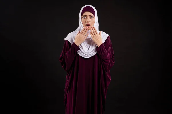 Arab woman in hijab shows astonishment.