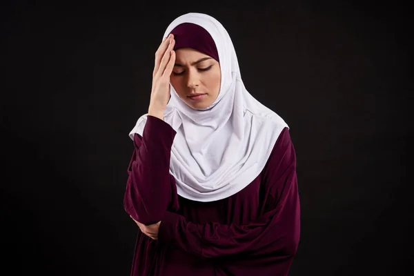 Mujer joven árabe en hiyab tiene dolor de cabeza . — Foto de Stock