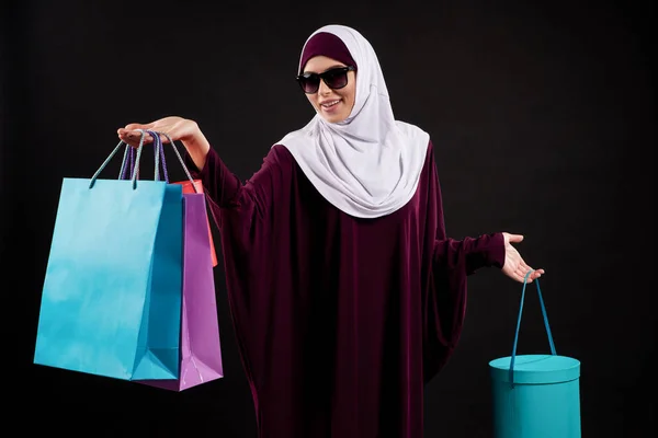 Arab woman in hijab and sunglasses holds paper