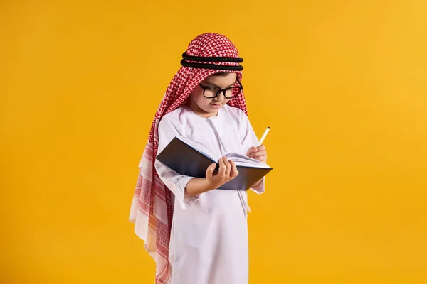Arabisk glad pojke med glasögon gör anteckningar — Stockfoto