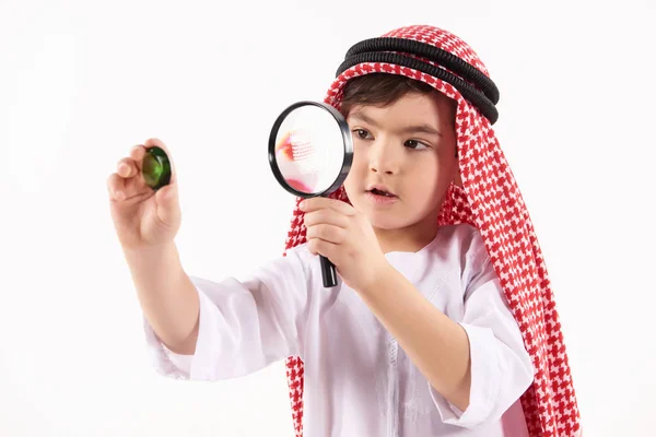 Arabian boy in keffiyeh examines precious stone — Stock Photo, Image