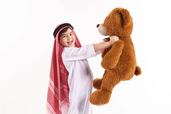 Arabian happy boy in keffiyeh hugs stuffed toy. — Stock Photo, Image