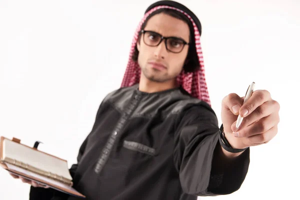 Arabisk man i huvudbonaden gör anteckningar i anteckningsboken. — Stockfoto