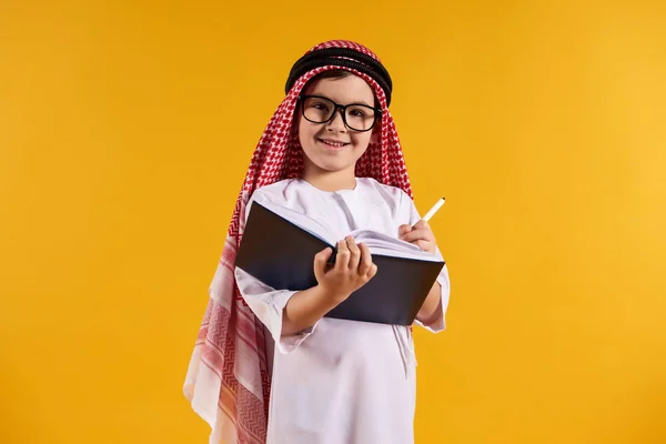 Arabové šťastný chlapec s brýlemi dělá poznámky — Stock fotografie