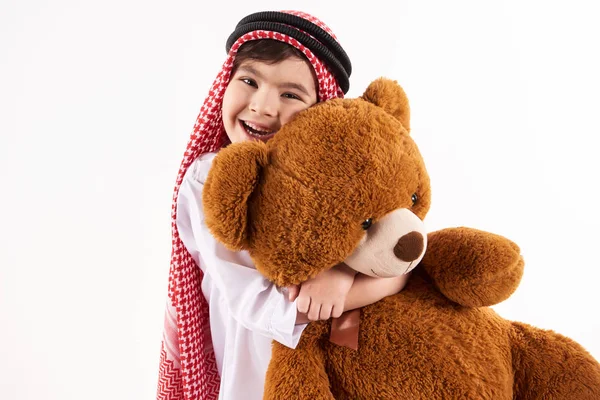 Arabian glad pojke i huvudbonaden kramar fyllda leksak. — Stockfoto