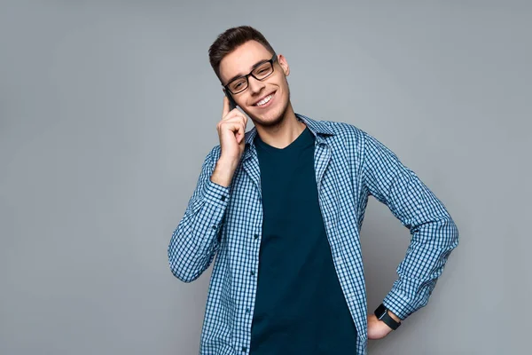 Young smart guy with glasses speaks on phone