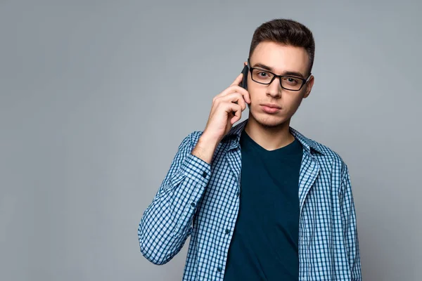 Young smart guy with glasses speaks on phone