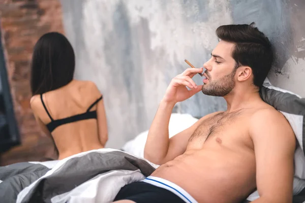 Homem apresentável fumando depois do sexo no quarto — Fotografia de Stock