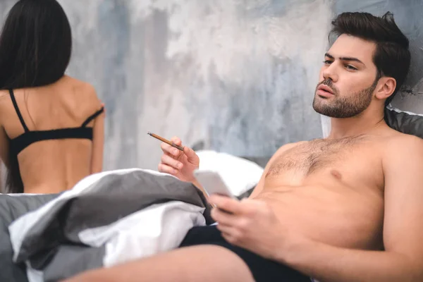 Eli yüzü düzgün adam yatak odasında seks sonra sigara — Stok fotoğraf