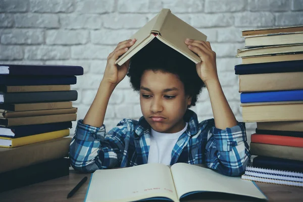 stock image African American schoolboy holds book over head