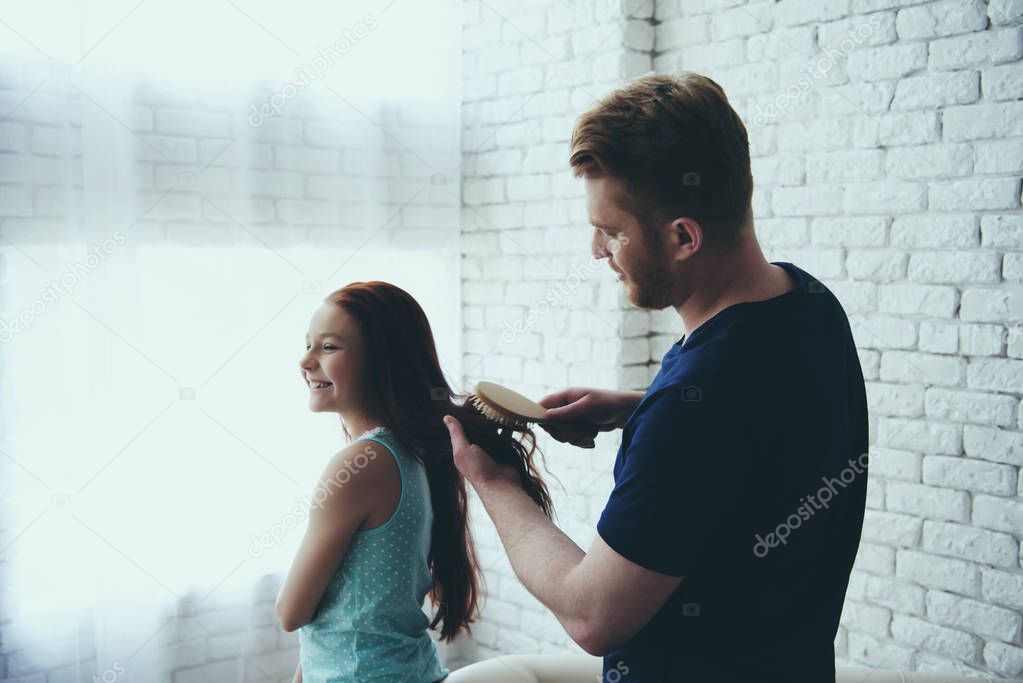 Young single father combs hair of red haired