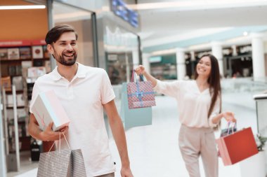Man and woman are walking from one store to another in shopping mall.