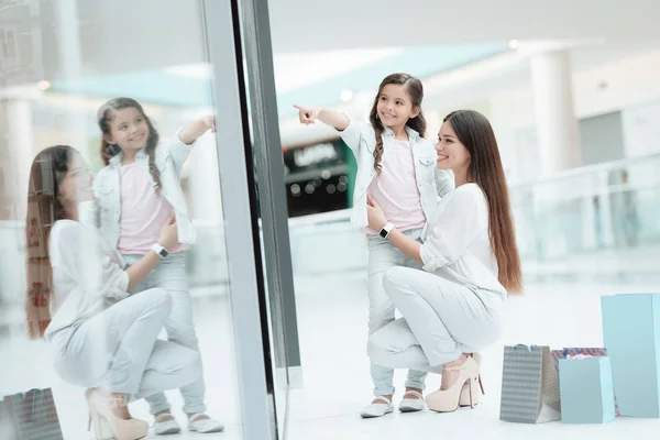 Dcera se sedí na klíně matky v shopping mall. Maminka a dívka se usmívají. — Stock fotografie