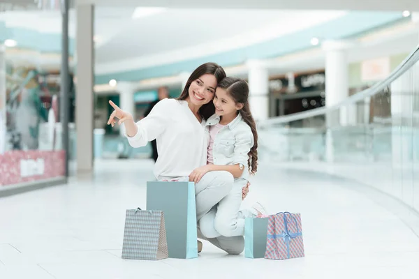 Die Tochter sitzt auf dem Schoß der Mutter im Einkaufszentrum. Mutter und Mädchen lächeln. — Stockfoto