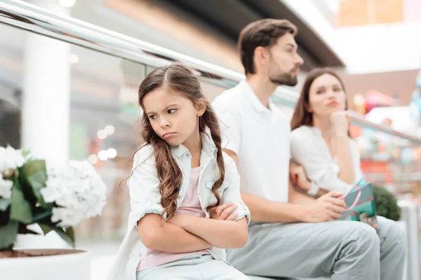 Familie, vader, moeder en dochter zitten op bankje in winkelcentrum. Meisje is boos en verdrietig. — Stockfoto
