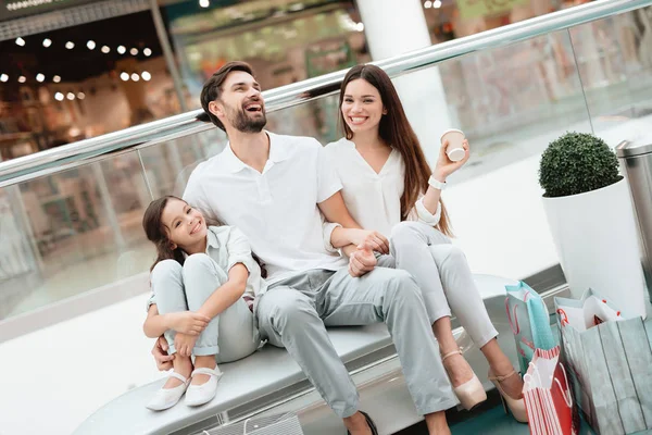 Dreiköpfige Familie, Vater, Mutter und Tochter sitzen auf Bank in Einkaufszentrum. — Stockfoto