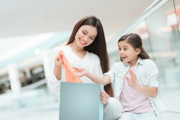 Matka a dcera jsou vytáhl nový svetr v shopping mall. Dívka se těší. — Stock fotografie
