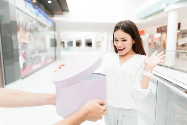 Mann und Frau in Einkaufszentrum. Mann überreicht Frau neue runde Schachtel Frau ist glücklich. — Stockfoto