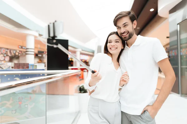 Hombre y mujer en el centro comercial. Pareja está tomando selfie con palo de selfie . — Foto de Stock