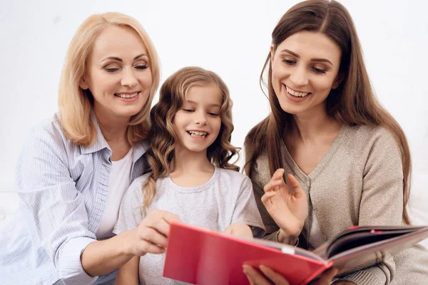 Drei Frauen unterschiedlichen Alters wählen Stil der Frisur in Katalog der Haarschnitte. — Stockfoto