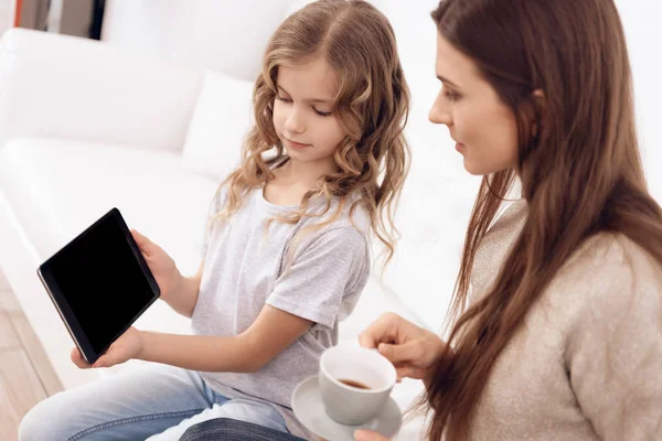 Krullend meisje met mooi bruin haar moeder Kies kapsel op Tablet PC. — Stockfoto