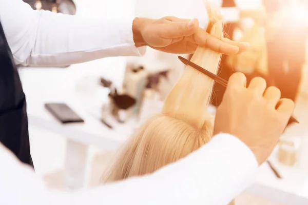 De cerca. Las manos de peluquero peinan el cabello rubio y recto de la mujer en el salón de belleza . —  Fotos de Stock