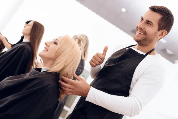 Peluquería femenina mostrando pulgares hasta mujer madura con hermoso peinado . —  Fotos de Stock