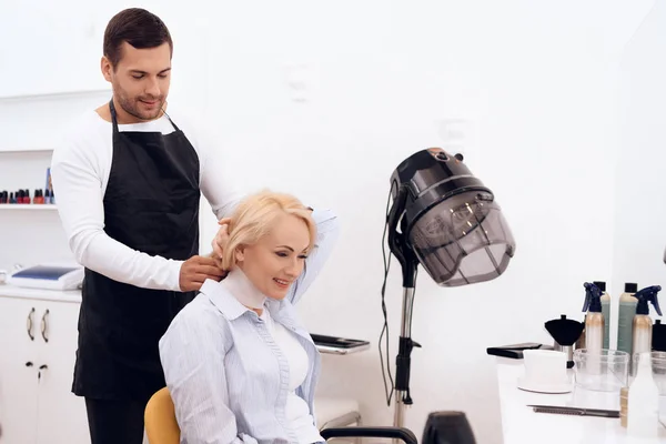 Mature pretty woman is doing hairdo in beauty salon. Female stylish haircut.