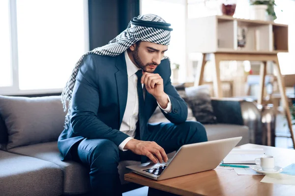 Arab businessman on lapton on couch at hotel room. — Stockfoto