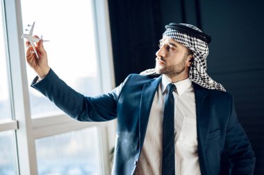 Arap işadamı pencere model uçak ile ayakta.