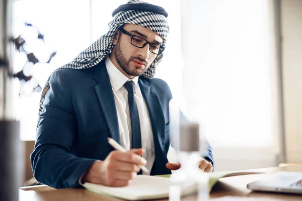 Arabischer Geschäftsmann macht sich Notizen am Tisch im Büro. — Stockfoto