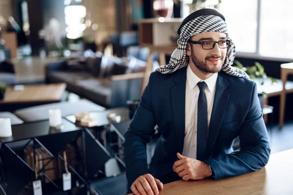 Arabische zakenman zitten aan de tafel op hotelkamer. — Stockfoto