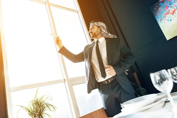Arabisk affärsman står vid fönstret med modellflygplan. — Stockfoto