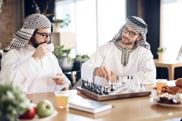 Två arabiska affärsmän som spelar schack vid bordet på hotellrummet. — Stockfoto