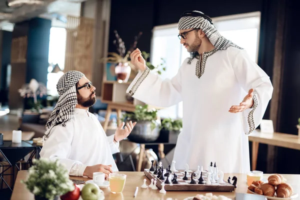 Två arabiska affärsmän argumentera spela schack vid bord på hotellrum. — Stockfoto