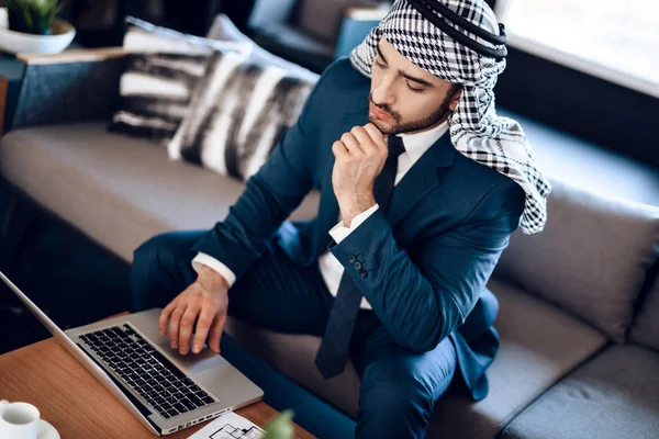 Arabischer Geschäftsmann auf Laptop auf Couch im Hotelzimmer. — Stockfoto