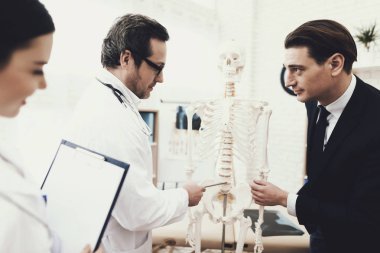 Physiiotherapist hasta vertebra omurga modelinde hastaya gösterir ve ağrısı neden açıklar.