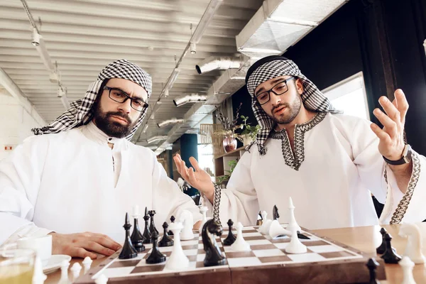 En arabisk affärsman checkmates en annan spela schack vid bord på hotellrum. — Stockfoto