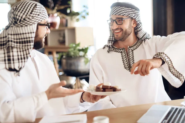 Twee Arabische zakenlieden aan tafel op hotelkamer met één bedrijf Turks fruit. — Stockfoto