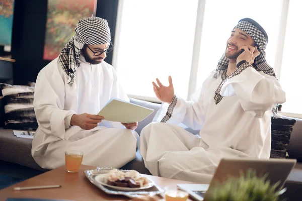 Twee Arabische zakenlieden met papieren op tafel op hotelkamer. — Stockfoto