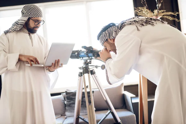 Twee Arabische zakenlieden met laptop en telescoop op hotelkamer. — Stockfoto