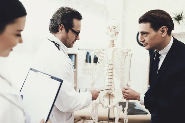 Fisiioterapeuta muestra vértebras enfermas en el modelo de columna vertebral al paciente y explica la causa del dolor . —  Fotos de Stock
