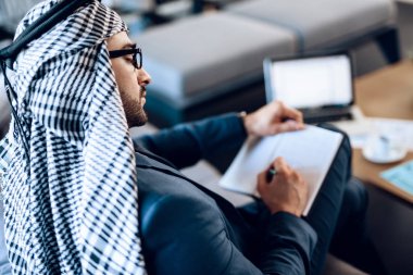 Arap işadamı kanepede oda ofis, not alma.