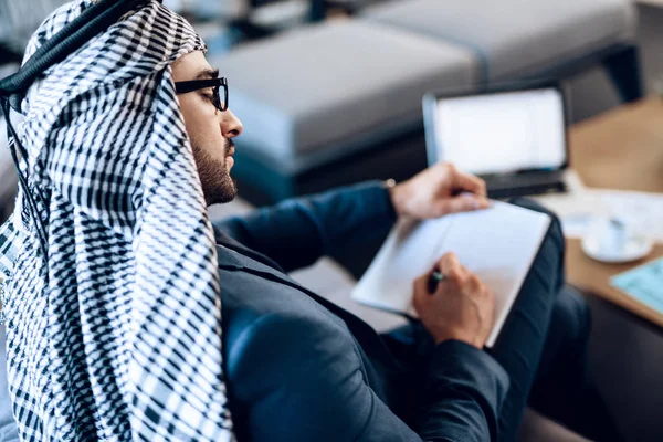 Arabischer Geschäftsmann macht sich Notizen auf Couch im Büro. — Stockfoto